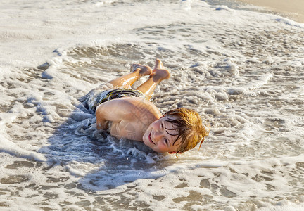 小男孩躺在沙滩上玩泡沫图片