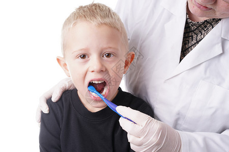 年轻男孩得到牙医的帮助刷牙图片