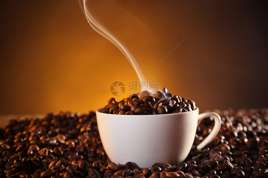 深色背景中的一杯咖啡和咖啡豆图片