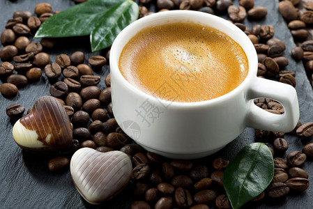 咖啡豆背景上的浓缩咖啡和心形巧克力糖图片