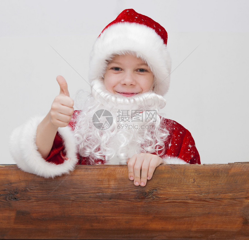 穿着圣诞老人帽子的小男孩用拇指举起标牌图片
