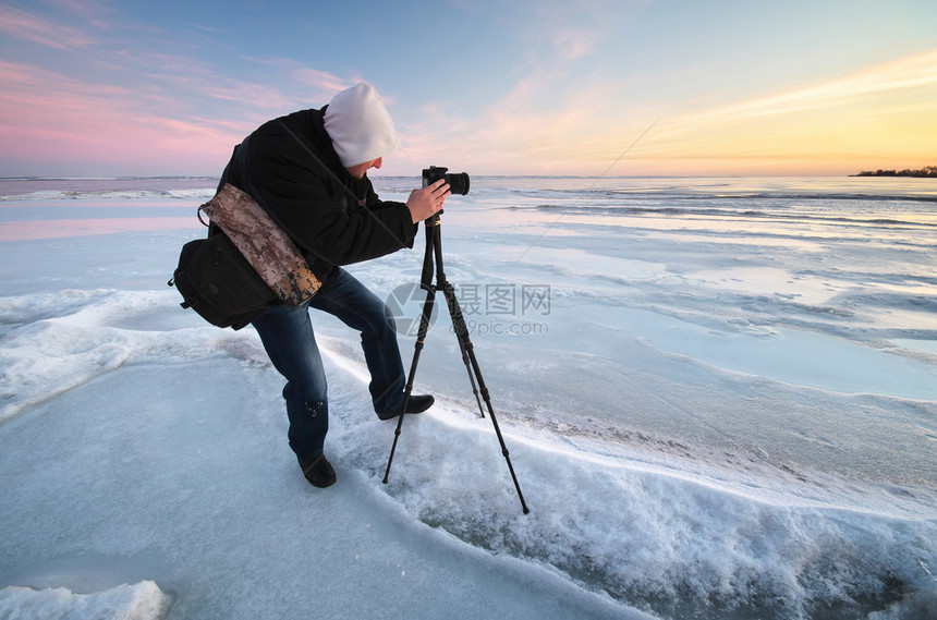 摄影师在冬天的河岸上拍照图片