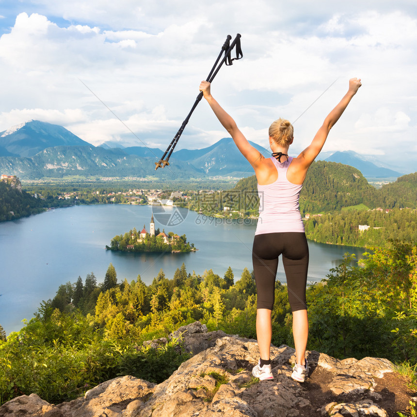 它让年轻有色人种活跃的女士带着徒步木棍和手仰慕着美丽的自然在斯洛文尼亚朱利安阿尔卑斯的图片