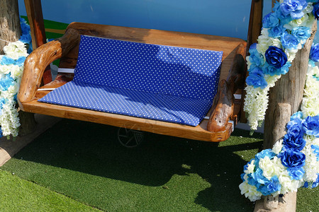 用蓝色和白色人造花朵装饰的木形摇椅垫上图片