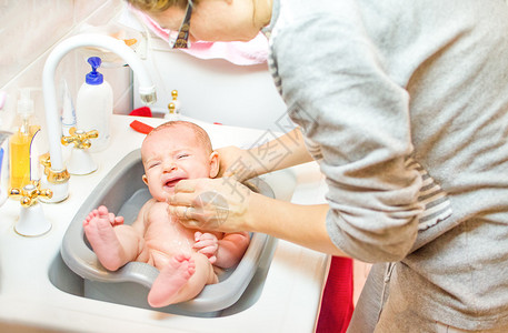 婴儿哭而母亲沐浴在浴室洗脸盆newbo图片