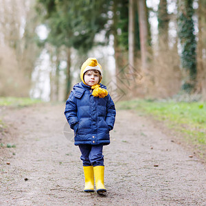 有趣的小孩男走在秋天的森林里黄色防水雨靴的孩子与孩子们在图片