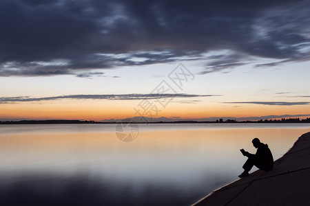 日落时在湖边读书的人剪影图片