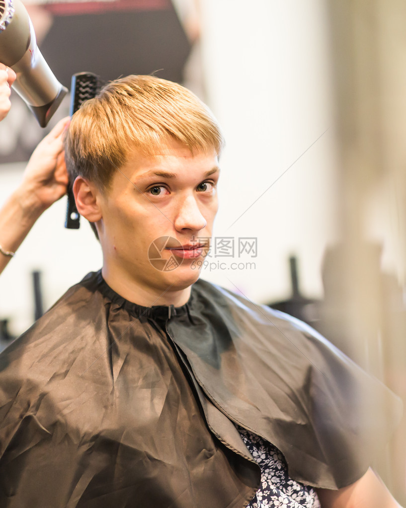 英俊的男人在理发师吹干他的头发图片