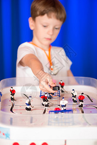 男孩打桌上曲棍球一个孩子在桌边举行曲棍球比赛小学生曲棍球裁判背景图片
