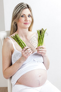拿着绿芦笋的孕妇肖像图片