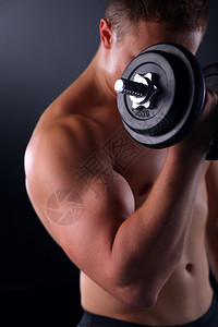 英俊的肌肉男用哑铃锻炼图片