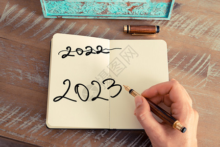 复古效果和女人手在笔记本上用钢笔写便条的色调图像带有手写文本的励志概念2023年和2022年新背景图片