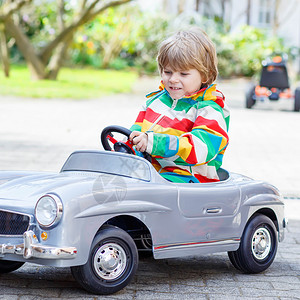 两个快乐的男孩朋友在春天或秋天的花园里玩大老式玩具车图片
