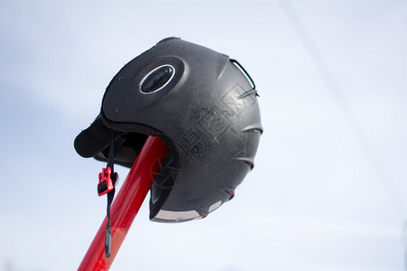 滑雪头盔挂在滑雪杖上照片是在滑过被雪覆盖背景图片