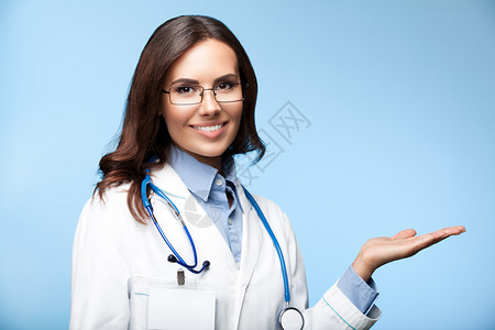 快乐笑的年轻女医生以明蓝背景展示标语或信息空版面或空白副图片