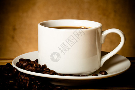 咖啡豆和白杯咖啡放在木制桌子上对面是焦图片