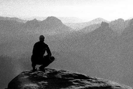黑色和白色的古草图破灭了孤独的时刻人类坐在岩石顶峰上图片
