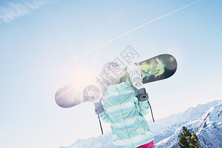 女滑雪板运动员戴着彩色头盔蓝色夹克灰色手套和粉色裤子图片