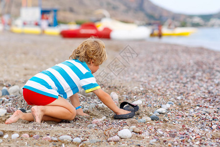 可爱的金发小男孩在海滩上建造鹅卵石城堡有趣的孩子独自玩耍假期图片