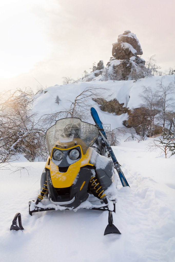 雪地摩托和滑雪在日落时的山脉背景图片