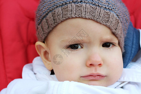 坐在婴儿车户外肖像机上坐在编织着的帽子图片