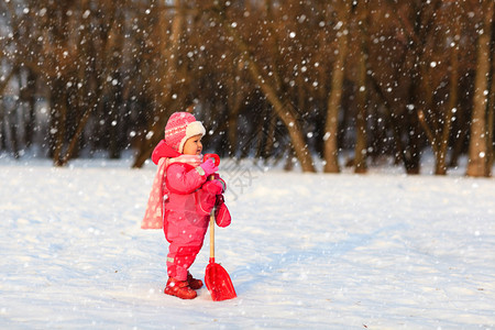 可爱的小孩姑娘在冬雪中挖洞孩子图片
