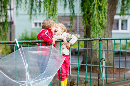 两个小孩在下雨天在户外打着大伞图片