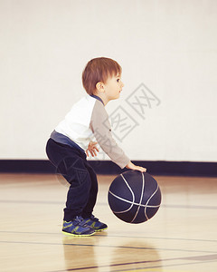 蹒跚学步的小男孩在健身房玩球图片
