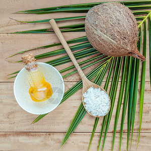 椰子油椰子粉和椰子在椰子叶上设置在棕色木质背景上图片