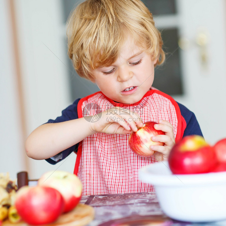 可爱的小孩男在室内家用厨房做苹果馅饼时玩得开心图片