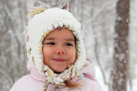 穿着温暖大衣和编织帽子的幼儿快乐女孩在冬季森林玩得开心图片