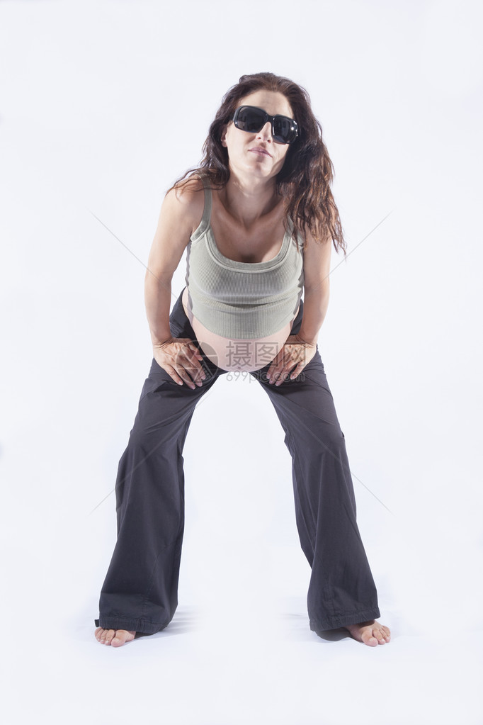 8个月的黑发孕妇裸露的胖子弯腰看着照相机带着墨镜黑色长裤在图片