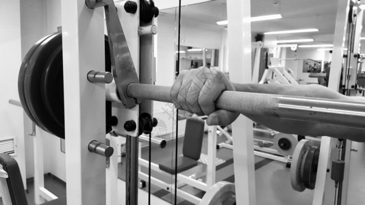 一名男子用杠铃进行锻炼健身房里的年轻举重运动员运动图片
