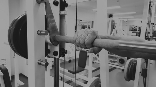 一名男子用杠铃进行锻炼健身房里的年轻举重运动员运动图片
