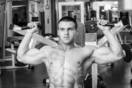 健身房里的肌肉男锻炼手臂肌肉在模拟器上训练在他的身图片