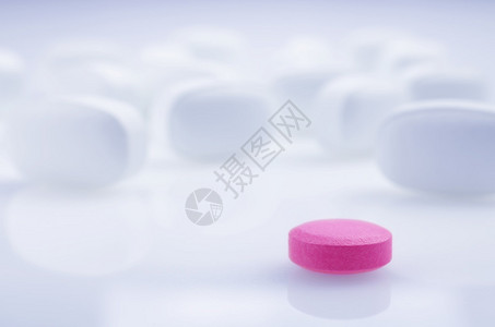 特写浅色背景上的粉红色药丸和白色药丸图片