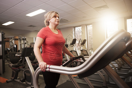成熟的女人在健身房的艰苦锻炼期间图片