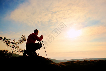 自然摄影师在悬崖上用三脚架思考图片