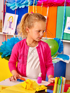 在幼儿园的桌子上拿着彩色纸的女孩儿童艺术课图片