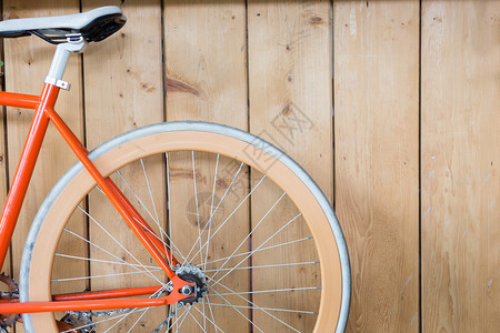 用木墙停放的橙黄色自行车关闭自行图片