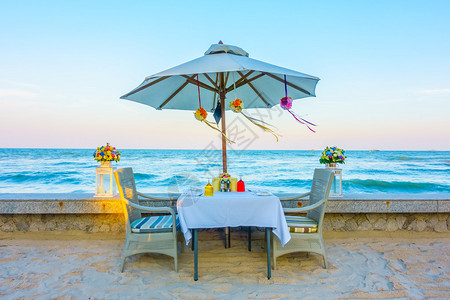 空桌和沙滩浪漫晚餐的椅子图片