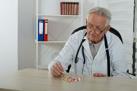 老医生在诊室里观察到很多药丸图片