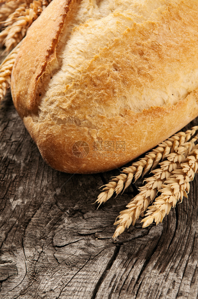 天然木质背景上带麦穗的面包特图片