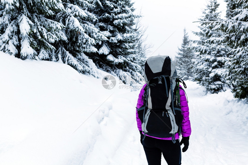 女人在白色的冬季森林里背着包徒步旅行或徒步旅行冬季自然的户外休闲健身和健康生活方式动机和鼓舞人图片