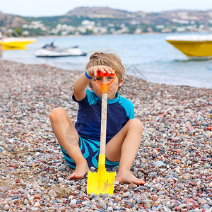 可爱的金发小男孩在海滩上建造鹅卵石城堡有趣的孩子在玩水桶和铲子假期图片