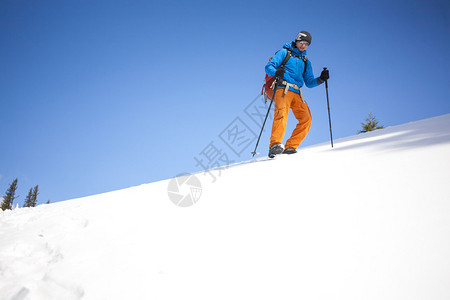 背着包的爬山者在雪坡图片
