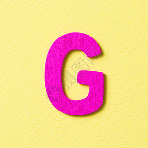 黄色背景中的木质纹理粉红色字母G图片