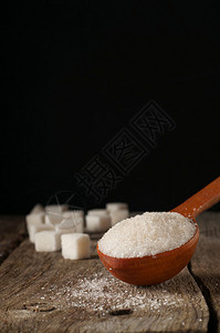 木制勺子和糖块中的白糖与方块图片