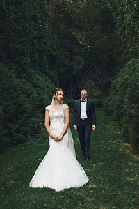 华丽优雅的豪华新娘和时尚的新郎在公园的树木背景图片