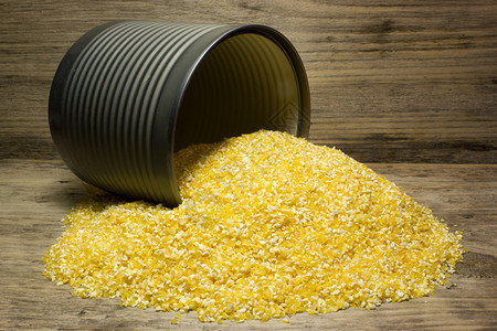 木制背景上的锡罐中的玉米糁图片